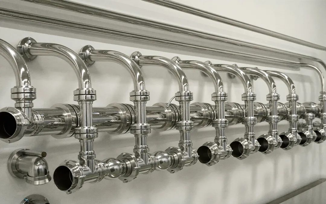 Tubo sanitario de acero inoxidable pulido con uniones clamp en una planta de procesamiento de alimentos